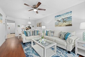 Un salon moderne avec un canapé blanc, une table basse en verre et un ventilateur de plafond.