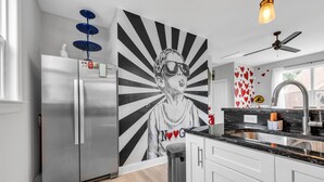 Una cocina moderna con un refrigerador de acero inoxidable, un mural en la pared y un ventilador de techo.