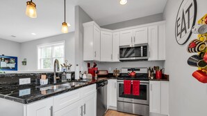 Una cocina moderna con gabinetes blancos, estufa de acero inoxidable y microondas.