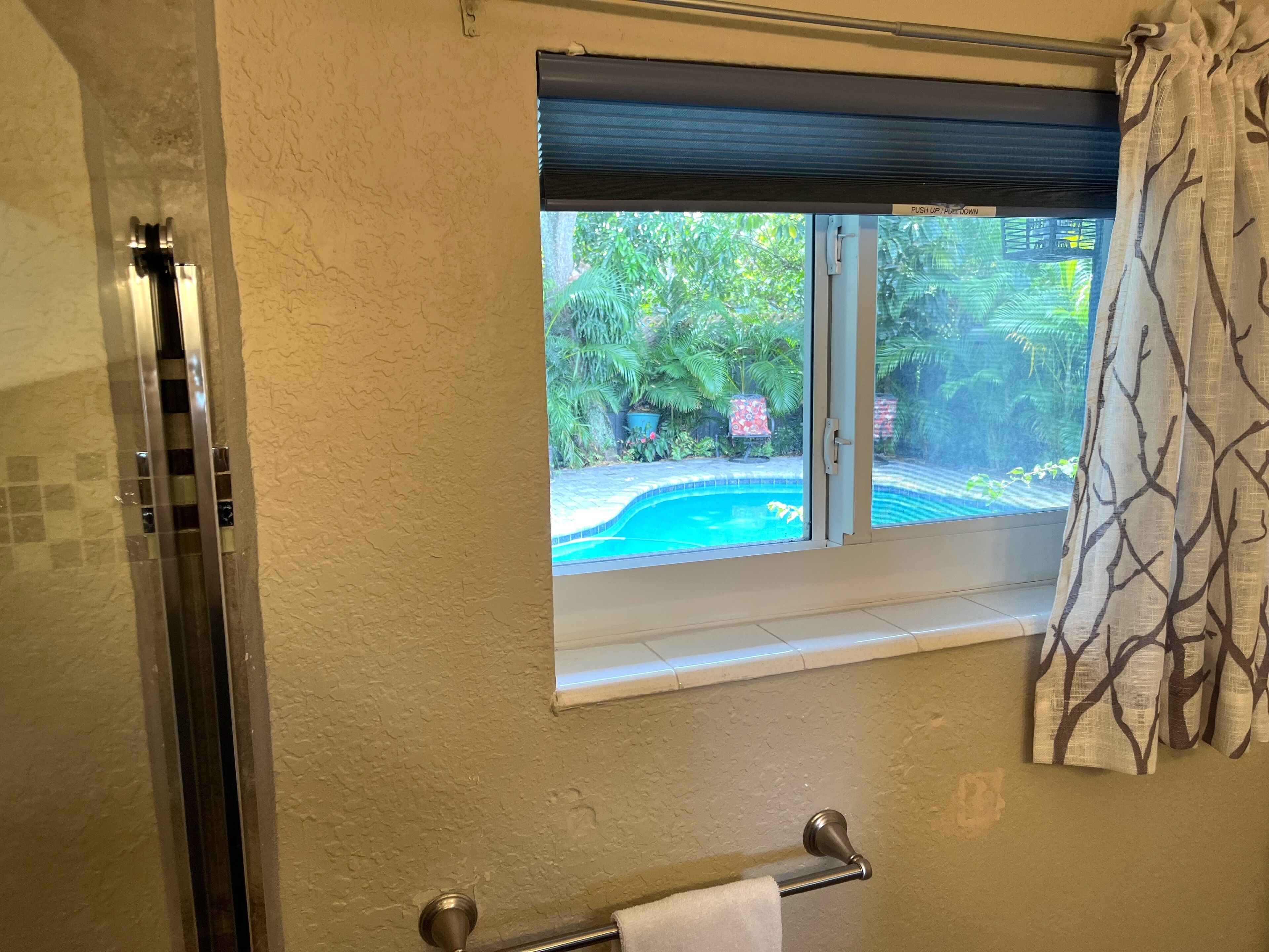 Un baño con ventana, toallero y zona de ducha.