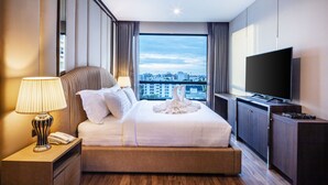 A modern hotel room with a large bed, a flat-screen TV, and a city view. - Grand Sala Thai (Bangkok)