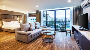A modern hotel room with a bed, sofa, round coffee table, TV, and a balcony with city views. - Grand Sala Thai (Bangkok)