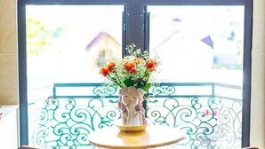 Una mesa con un jarrón de flores, dos sillas y una vista a través de un amplio ventanal.