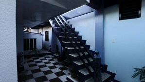 A modern staircase with a black and white checkered floor, leading to a second-floor area with a door and windows. - Keen's Place (Puerto Princesa)