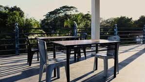 An outdoor patio with a table and chairs, surrounded by a railing with decorative elements. - Keen's Place (Puerto Princesa)