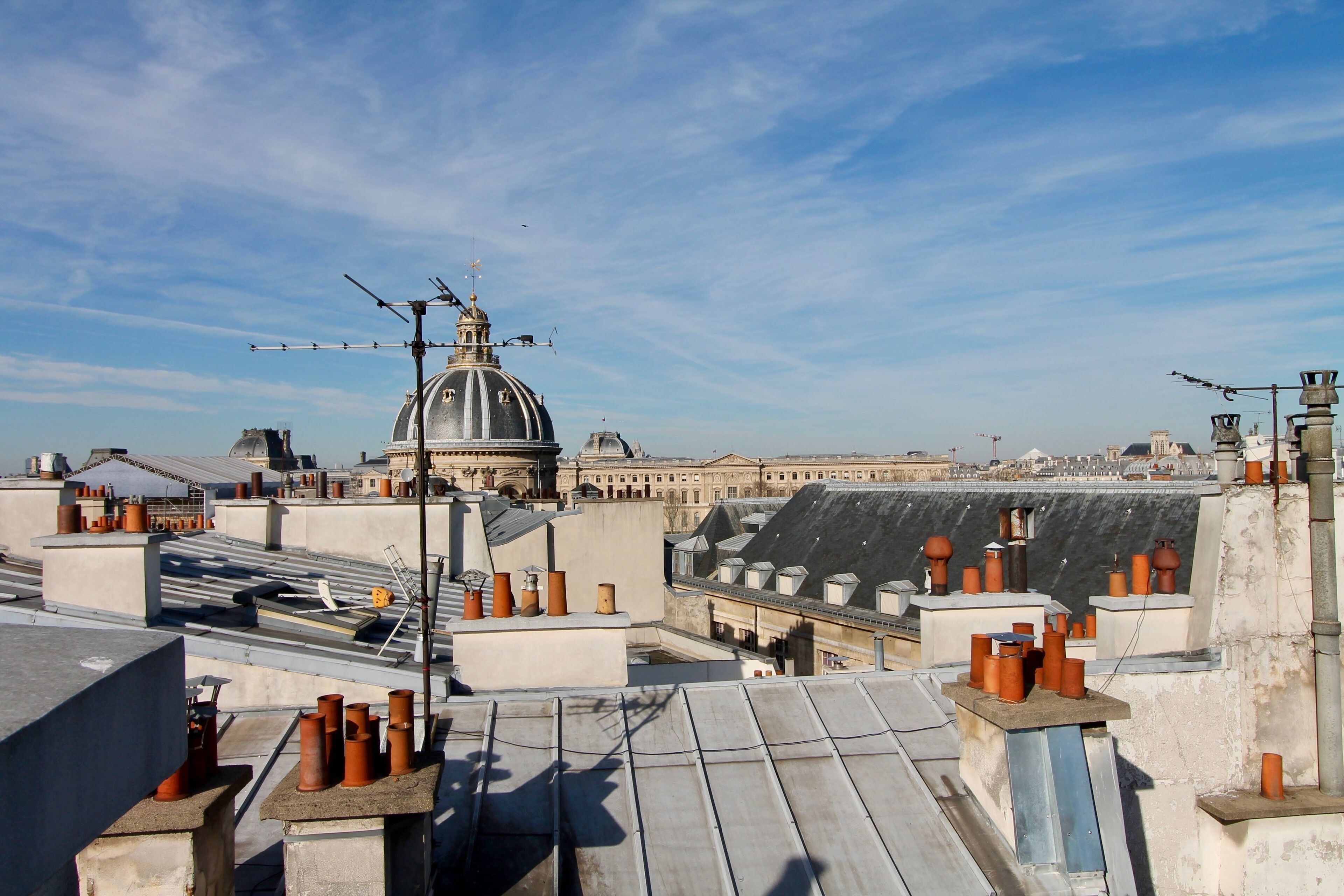 Terraço com vários vasos de terracota, uma antena de metal e uma grande estrutura em forma de cúpula ao fundo.