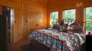 Une chambre dans une cabane en bois, avec un lit, des oreillers et une table de chevet.