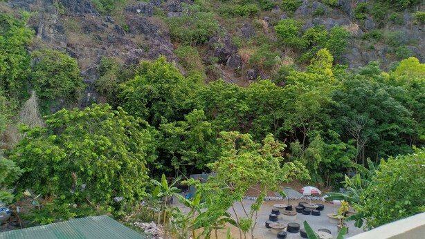 A view of a mountainous area with dense greenery and a seating area with tires and tables. - Starlet Hotel (Phong Nha)