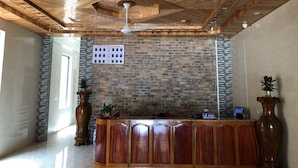 A reception area with a wooden ceiling, a brick wall, and a reception desk. - Starlet Hotel (Phong Nha)