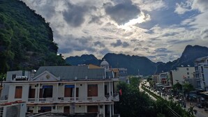 A building with a balcony and a flag, surrounded by greenery and mountains. - Starlet Hotel (Phong Nha)