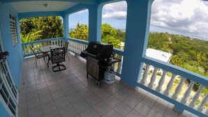 A covered balcony with a grill, a table, and chairs. - Casa Piña Apartment 2 (Rincon)
