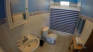 A bathroom with a sink, toilet, and a shower curtain. - Casa Piña Apartment 2 (Rincon)
