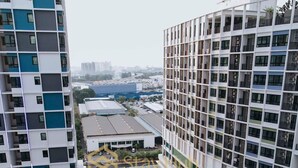 A high-rise building with a swimming pool surrounded by greenery and a view of the cityscape. - I City Theme Park Lux Home_link to mall_near UITM SCCC (I-City)