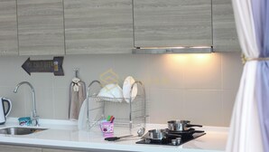 A modern kitchen with wooden cabinets, a stainless steel sink, and a range hood. There is a dish rack with plates and a sign indicating "Ice Cold Beer." - I City Theme Park Lux Home_link to mall_near UITM SCCC (I-City)