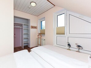 Une chambre à coucher avec un lit, une armoire, un radiateur et une fenêtre.