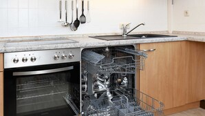 Een keuken met houten kastjes, een ingebouwde oven, een vaatwasser en een RVS afzuigkap.