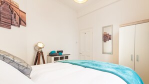 Une chambre à coucher comprenant un lit, une table de chevet avec une lampe, une armoire et un miroir fixé au mur.