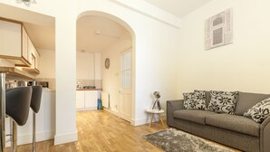 Un salon moderne avec un canapé gris, une petite table d’appoint et un tapis moelleux.