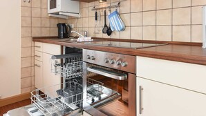 Una cocina con armarios blancos, horno empotrado, microondas y lavavajillas.