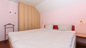 Un dormitorio con una cama grande, un armario de madera y dos luces fijadas a la pared.