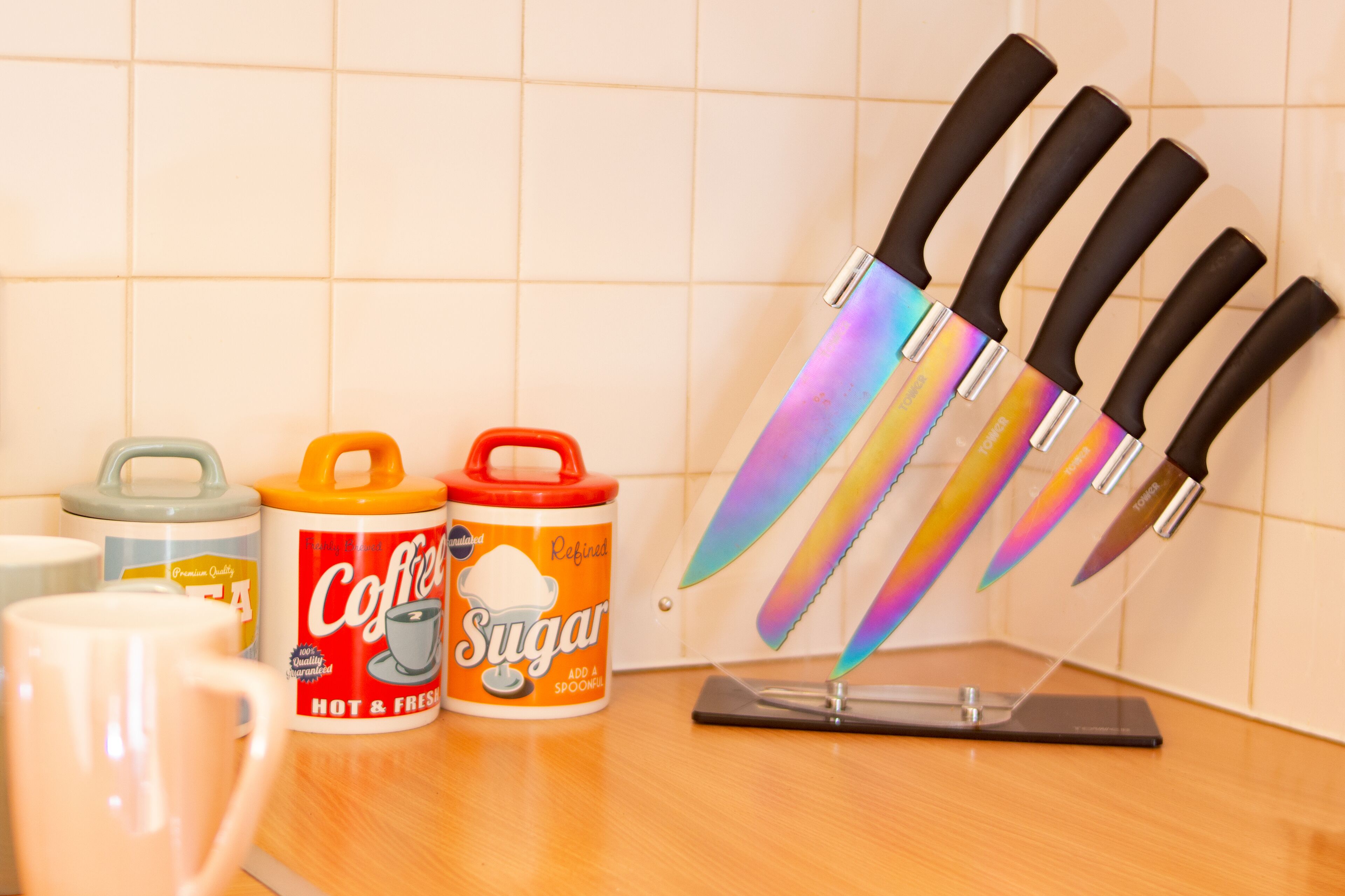 A kitchen counter with a coffee can, a sugar can, and a knife block.