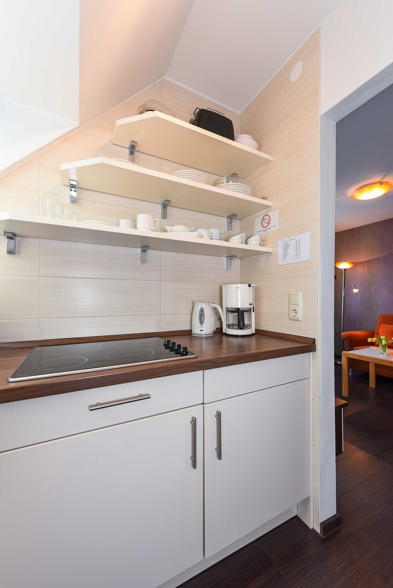 A modern kitchen with white cabinets, a built-in stove, and a coffee maker.