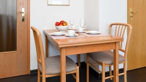 Un coin repas avec une table et des chaises en bois, un tableau encadré au mur et une porte dotée d’un panneau en verre.