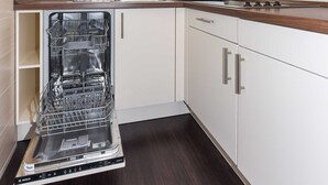 Une cuisine compacte équipée d’un lave-vaisselle, d’un four à micro-ondes et d’une fenêtre située au-dessus de l’évier.