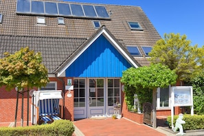 Um edifício com fachada azul, exterior de tijolo e telhado inclinado com painéis solares.
