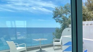 Una terraza con sillas de descanso y una mesa con vista al mar.