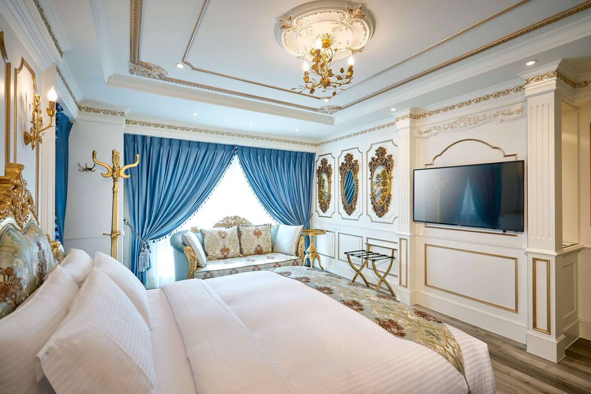A luxurious bedroom with a large bed, a television, and ornate wall decorations.