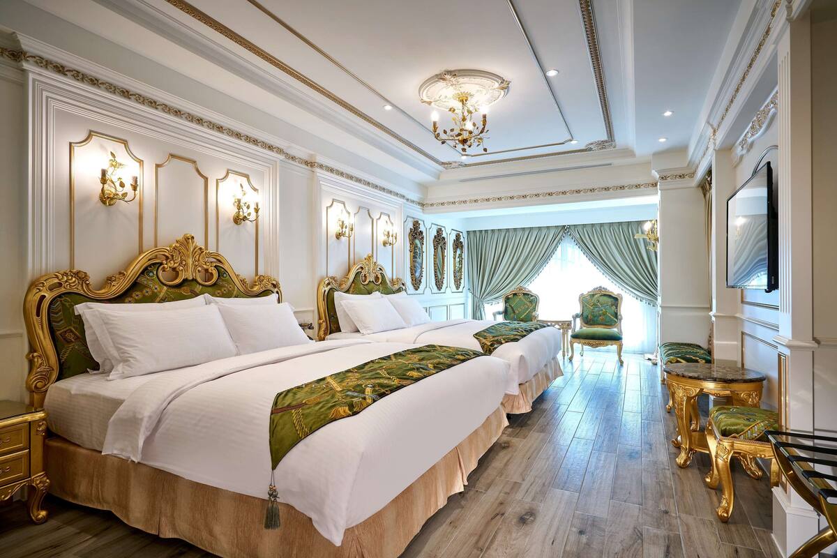 A luxurious bedroom with a large bed, ornate headboard, and a chandelier.