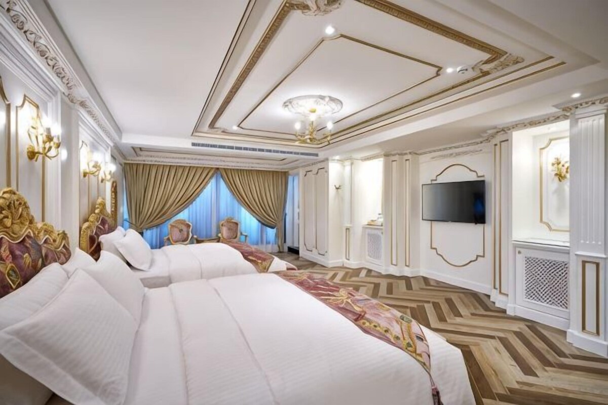Une chambre à coucher luxueuse, dotée d’un grand lit, d’une télévision et d’un lustre.