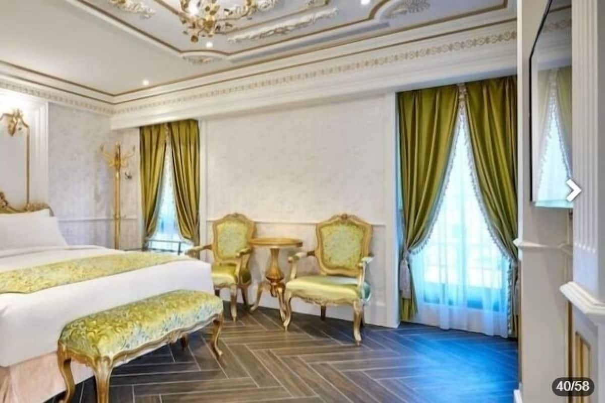 A luxurious hotel room with a large bed, ornate furniture, and classic decor.