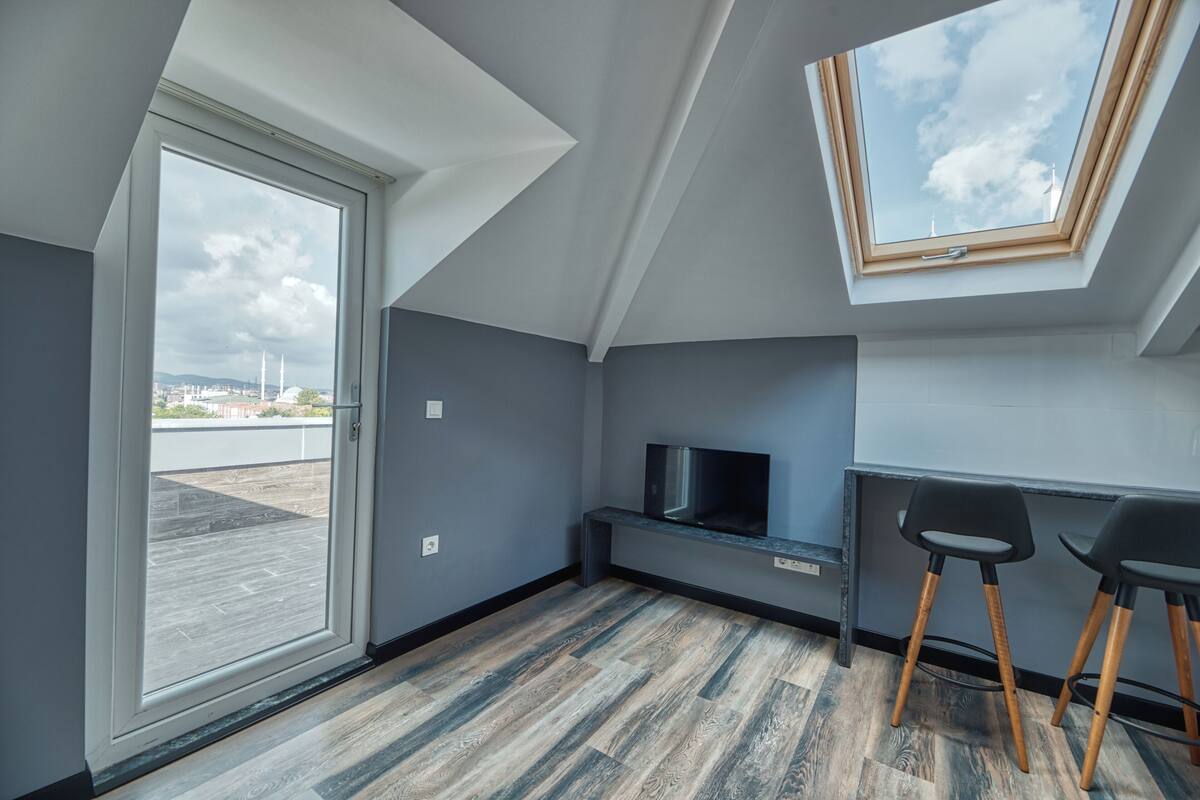 Un appartement moderne doté d’une lucarne, d’un téléviseur posé sur un meuble noir et d’un plancher en bois.