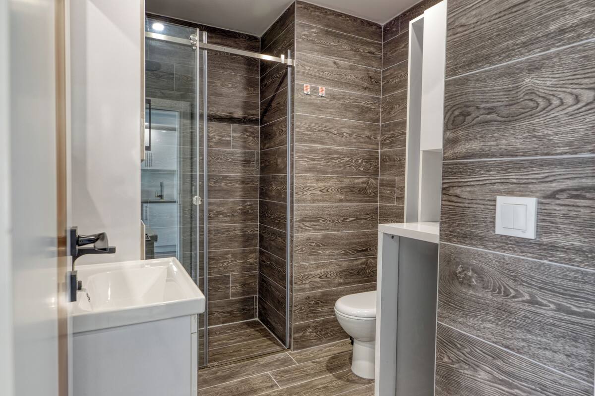 Une salle de bain moderne avec une douche à parois de verre, un lavabo blanc et des toilettes.