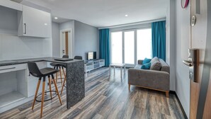 A modern apartment with a kitchen, dining area, and living room. It features a grey sofa, a coffee table, and a TV. - Grisverde Suites Hotel (Istanbul)