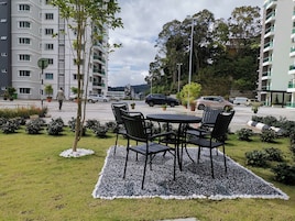 Un patio con una mesa y sillas, rodeado de grava, y edificios al fondo.