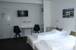 A hotel room with a bed, two chairs, a desk, a television, and a wall with pictures. - Motel Poppelvej (Herning)