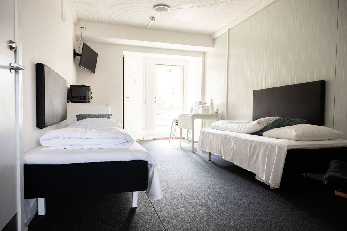 A hotel room with two beds, a desk, and a TV mounted on the wall.