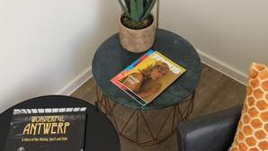 A small round table with a magazine and a potted plant. - Citystay (Antwerp)