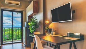 Un espace repas moderne doté d’une grande fenêtre, d’un téléviseur à écran plat fixé au mur et d’une table à manger avec des chaises.