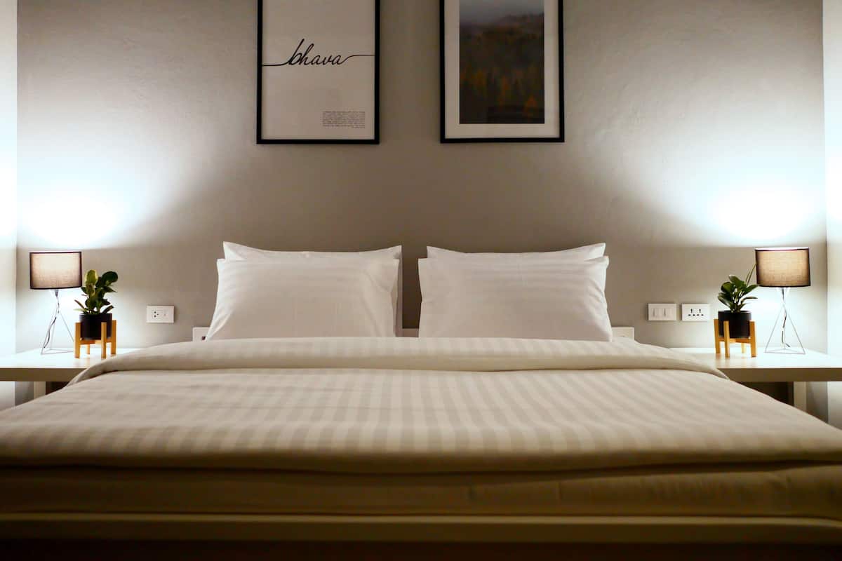 Ein Hotelzimmer mit einem großen Bett, zwei Nachttischen mit Lampen und gerahmten Kunstwerken an der Wand.
