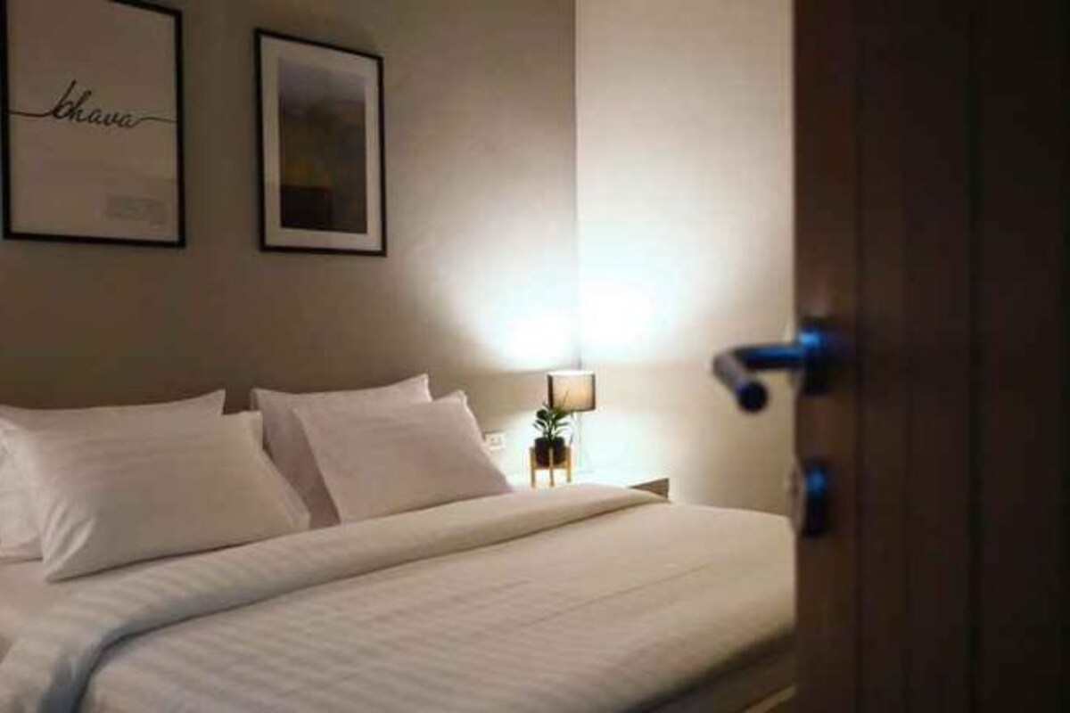 A hotel room with a bed, a nightstand, a lamp, and framed artwork on the wall.