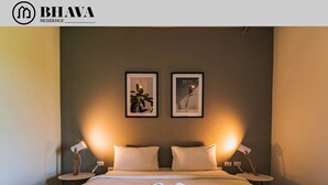 Une chambre d’hôtel avec un grand lit, deux tables de chevet et une lampe de chevet. On trouve un plateau avec des serviettes et des articles de toilette sur le lit.