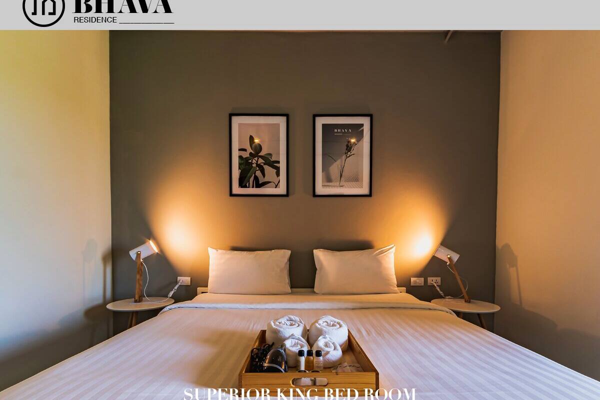Ein Hotelzimmer mit einem großen Bett, zwei Nachttischen und einer Nachttischlampe. Auf dem Bett befindet sich ein Tablett mit Handtüchern und Toilettenartikeln.