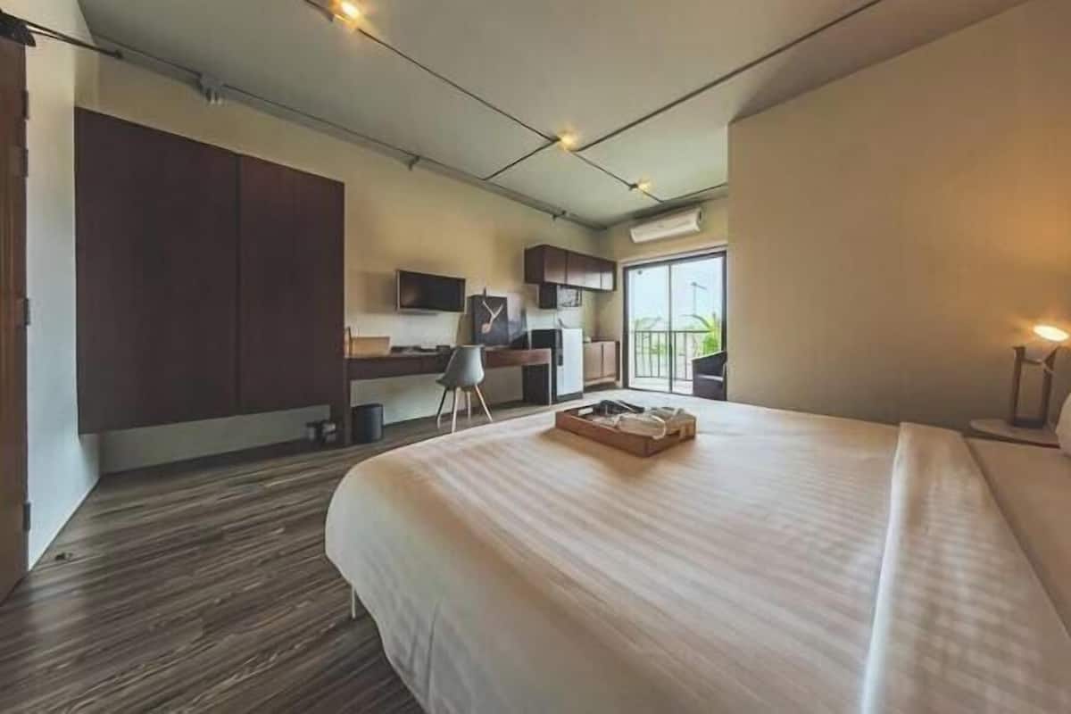Una habitación de hotel moderna con una cama grande, un escritorio y una kitchenette.