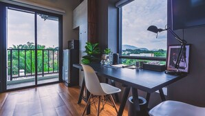 Une cuisine moderne dotée d’une grande fenêtre, un coin repas avec une table et des chaises, et une vue sur la verdure et les collines.