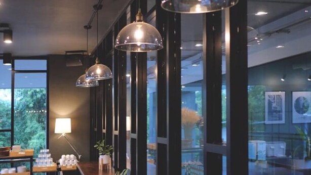 Un intérieur moderne agrémenté de luminaires suspendus, de tables en bois et de plantes en pot.