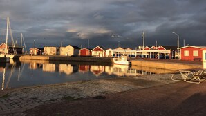 En hamn med båtar, en röd byggnad och en stilla vattenyta som speglar himlen.